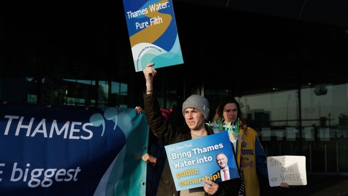 Protesters outside City Hall in London holding signs saying ‘Thames Water - pure filth’