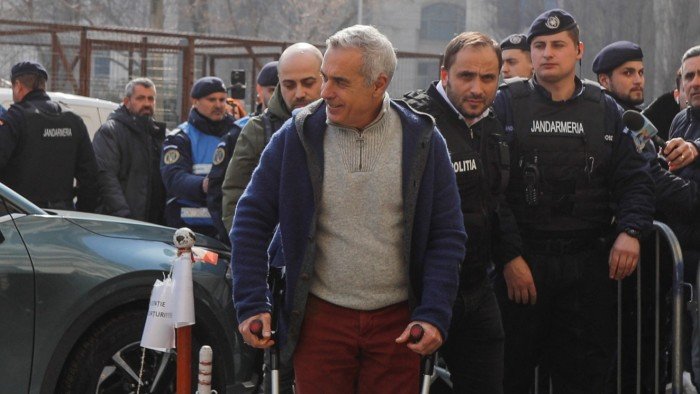 Calin Georgescu, is escorted by police officers inside the prosecutor’s office