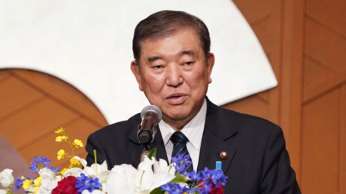 Shigeru Ishiba delivers a speech at at a podium adorned with colourful flowers