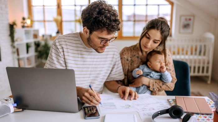 Parents with a  young baby pore over papers next to an open laptop on a table