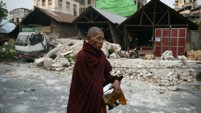 A monk walks past damaged houses in Mandalay on Sunday