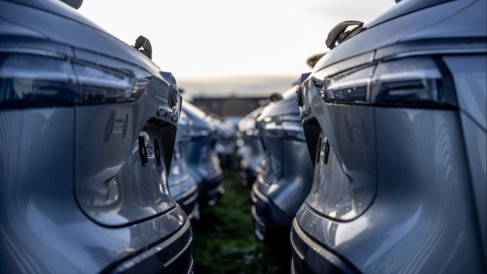 Rows of silver cars are parked closely together, facing away from the camera