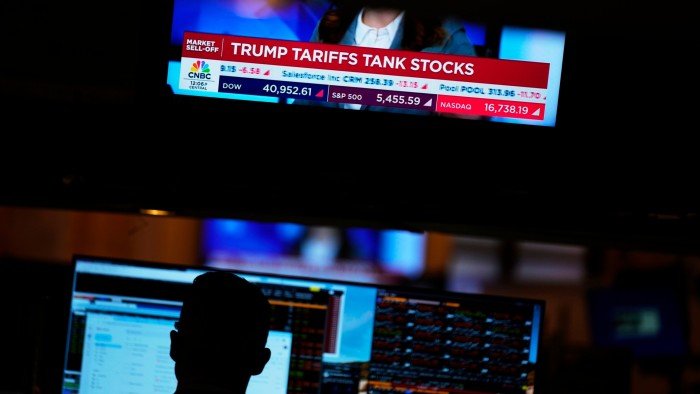 A screen displays financial news as traders work on the floor at the New York Stock Exchange on April 3 2025