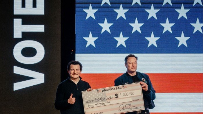 Elon Musk presents a $1mn cheque to an attendee at an America PAC town hall ahead of the Wisconsin Supreme Court election