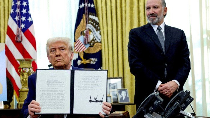 Donald Trump holds an executive order about tariffs increase, flanked by US commerce secretary Howard Lutnick, in the Oval Office of the White House