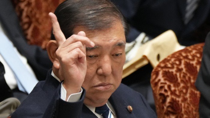 Japan’s Prime Minister Shigeru Ishiba raises his hand