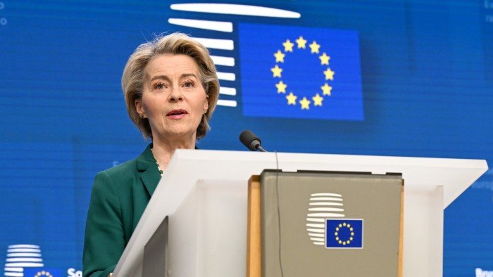 Ursula von der Leyen speaks at a podium during a press conference with the EU flag in the background