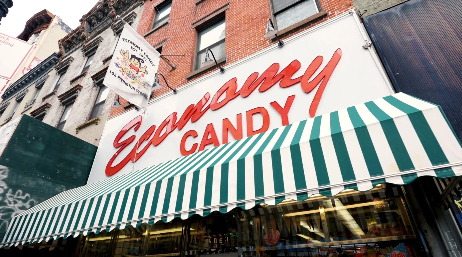 New York City: A white and green striped storefront awning below a white sign with red text reading